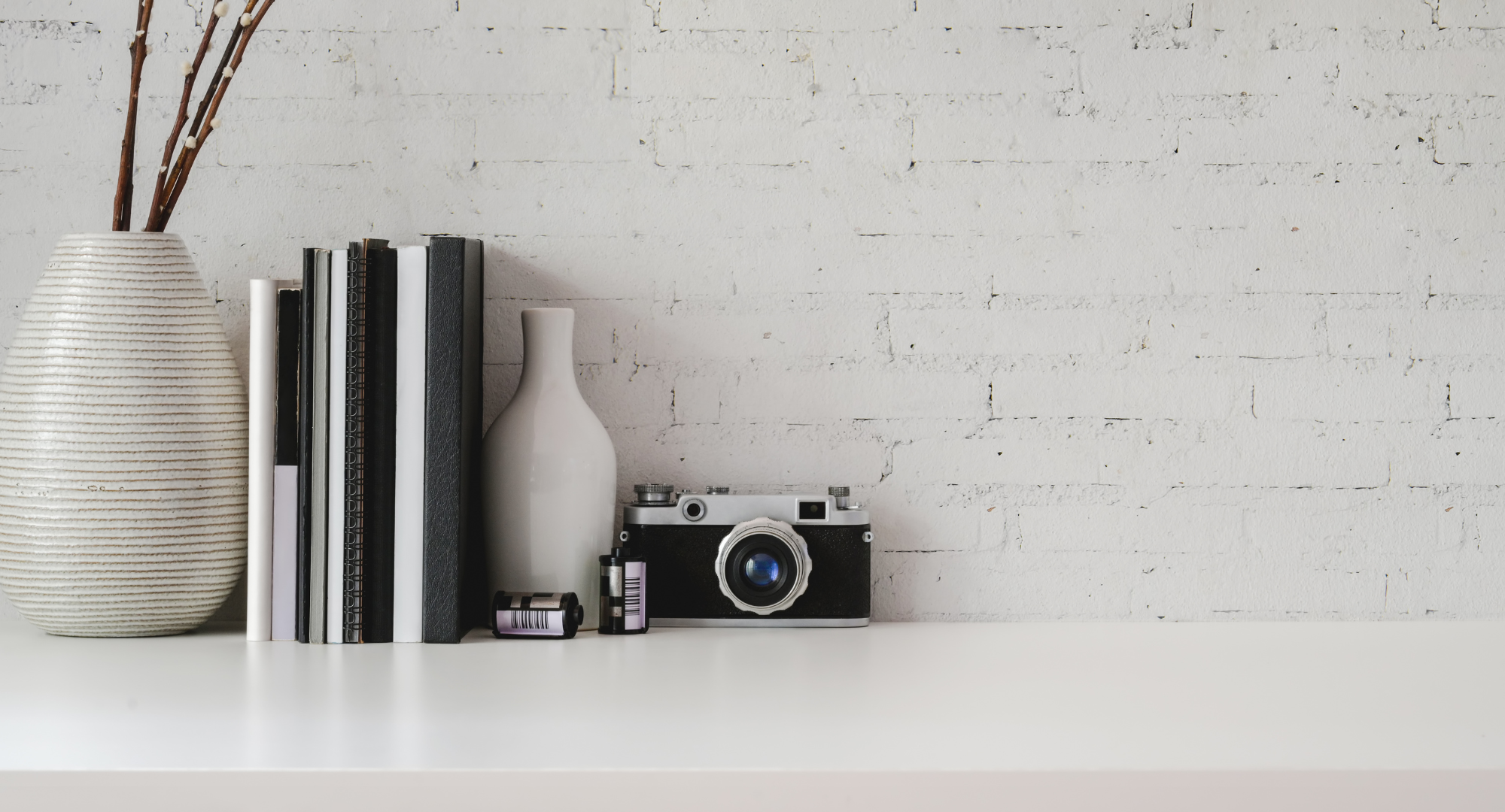 a clean countertop with a few minimal items including books, a vase and a camera 