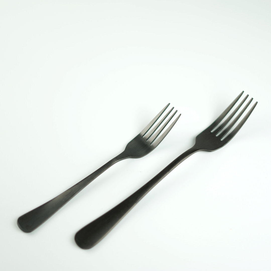 A large and small matte black fork laid on a white surface