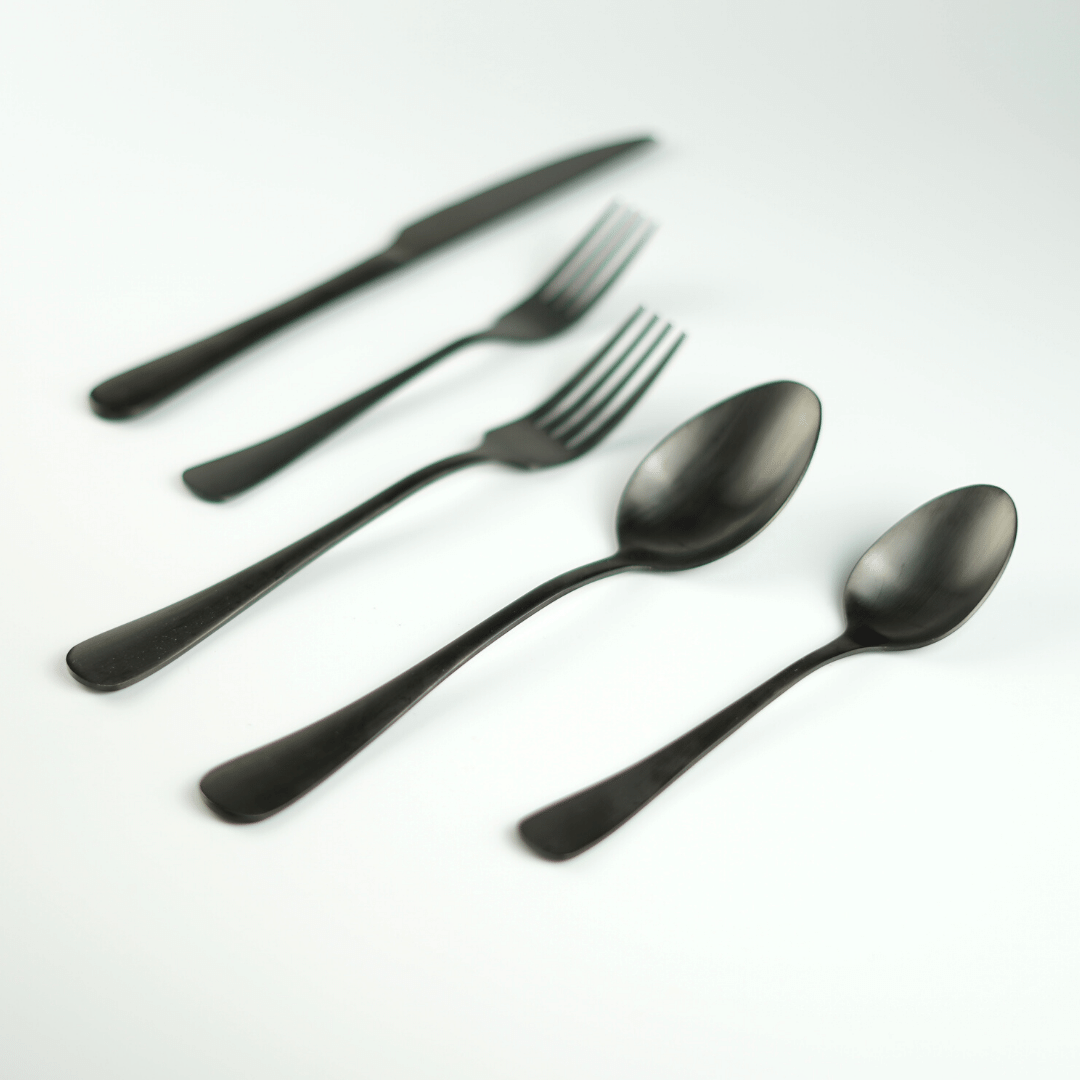 Black matte cutlery set laid out on a white surface